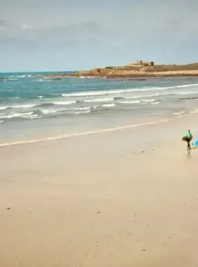 Surfers on a wide sandy beach