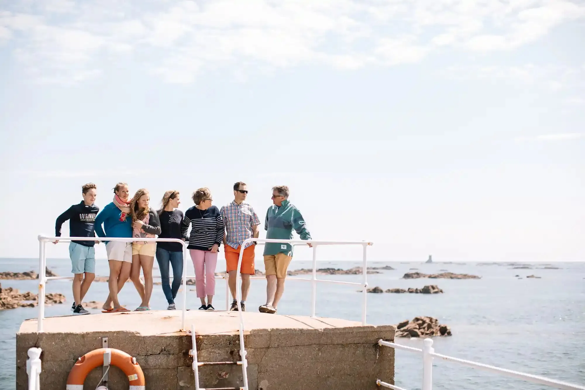 A group of friends on a harbour wall by the sea